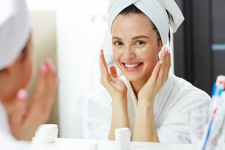 young woman uses moisturizer after shower