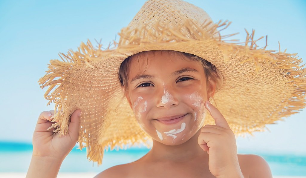 young girl putting sunscreen on