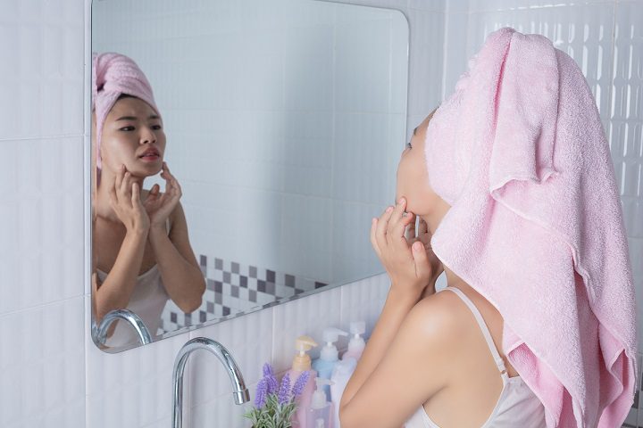 girl squeezes pimples in mirror