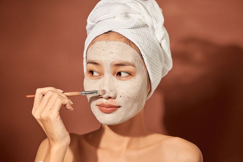 young asian woman applies clay mask