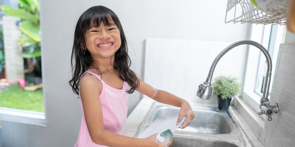 little girl washes dishes with natural soap