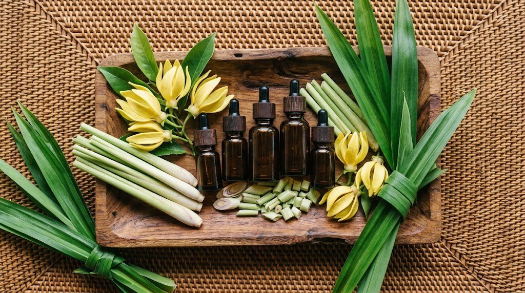 essential oil blends arranged on Balinese teak tray with fresh botanicals