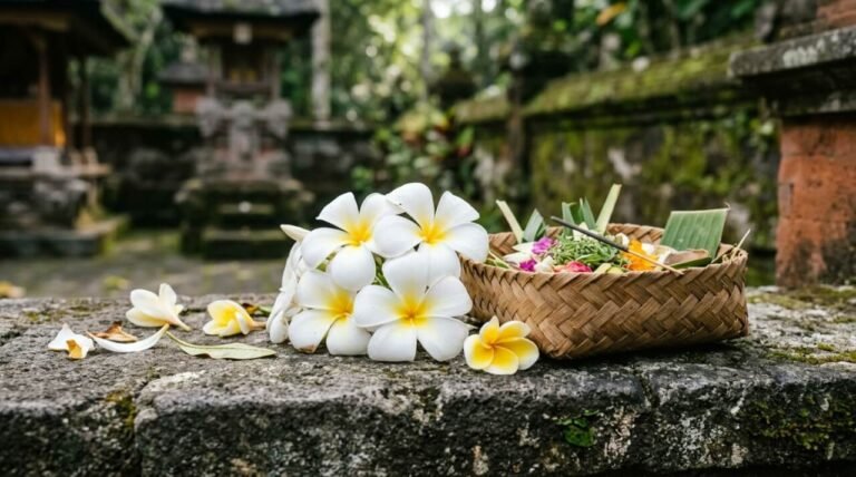 White frangipani blossoms on a stone temple ledge beside a woven offering tray